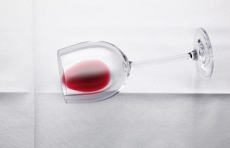 Weinglas auf weißer Tischdecke. Rotwein. Glas umgekippt